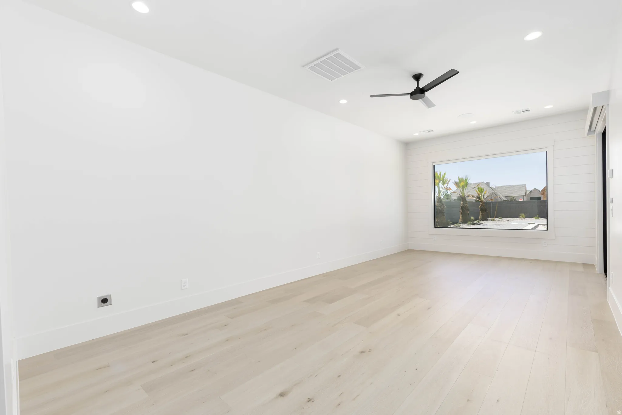 Light wood-finish flooring with recessed lighting and a ceiling fan