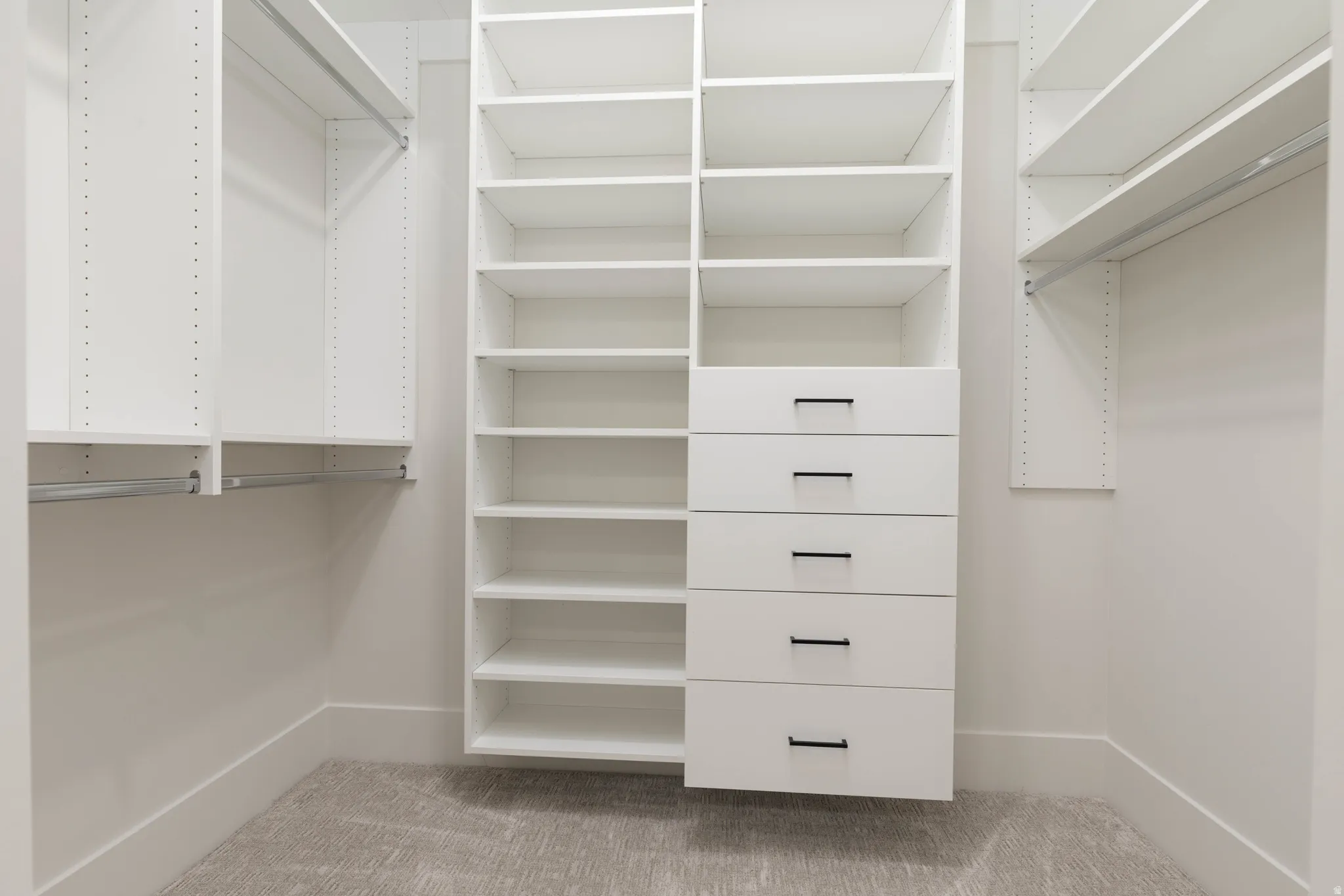 Custom closet system featuring white shelving and drawers with matte black hardware