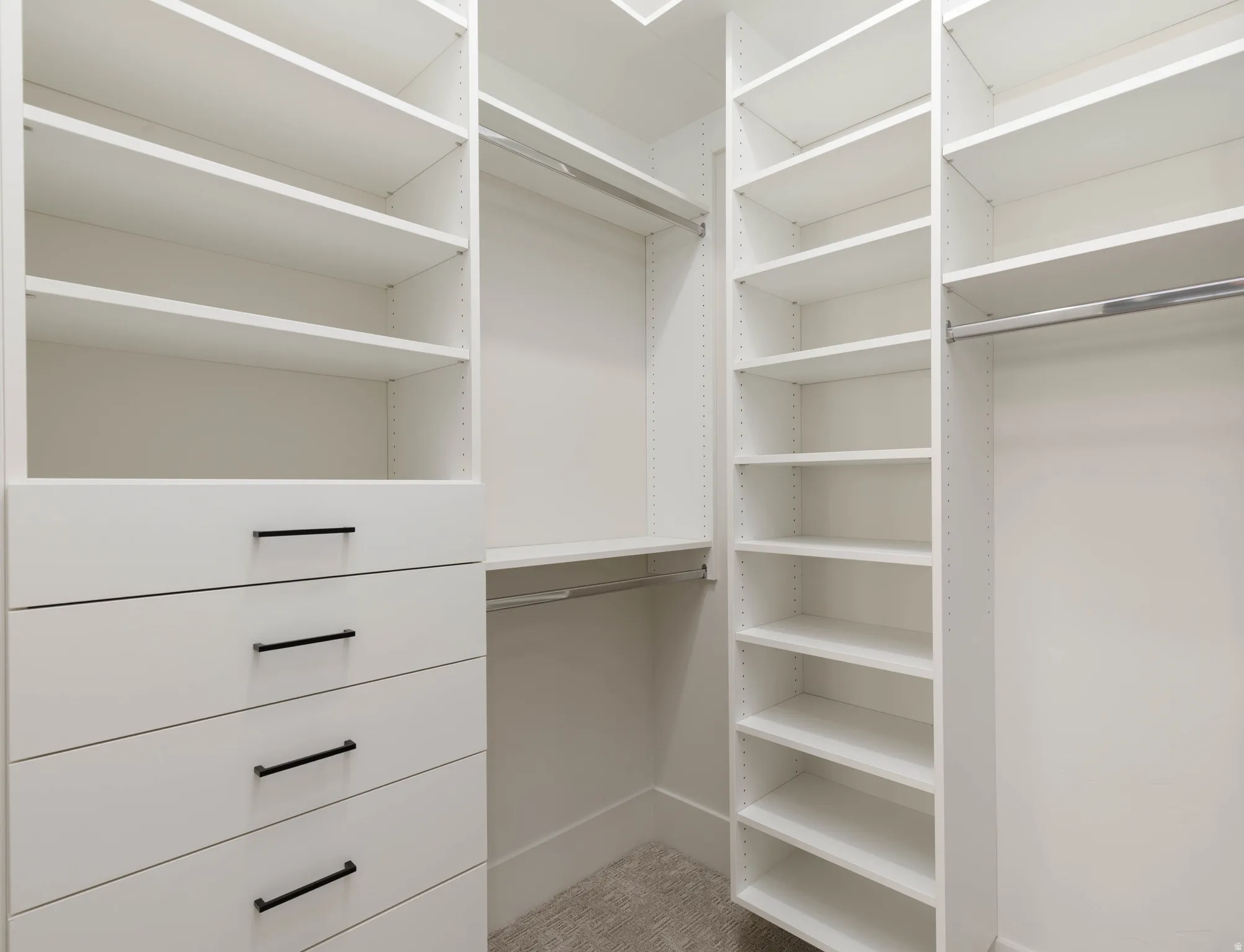 Built-in closet system featuring white shelving, multiple hanging rods, and integrated drawer storage with matte black hardware