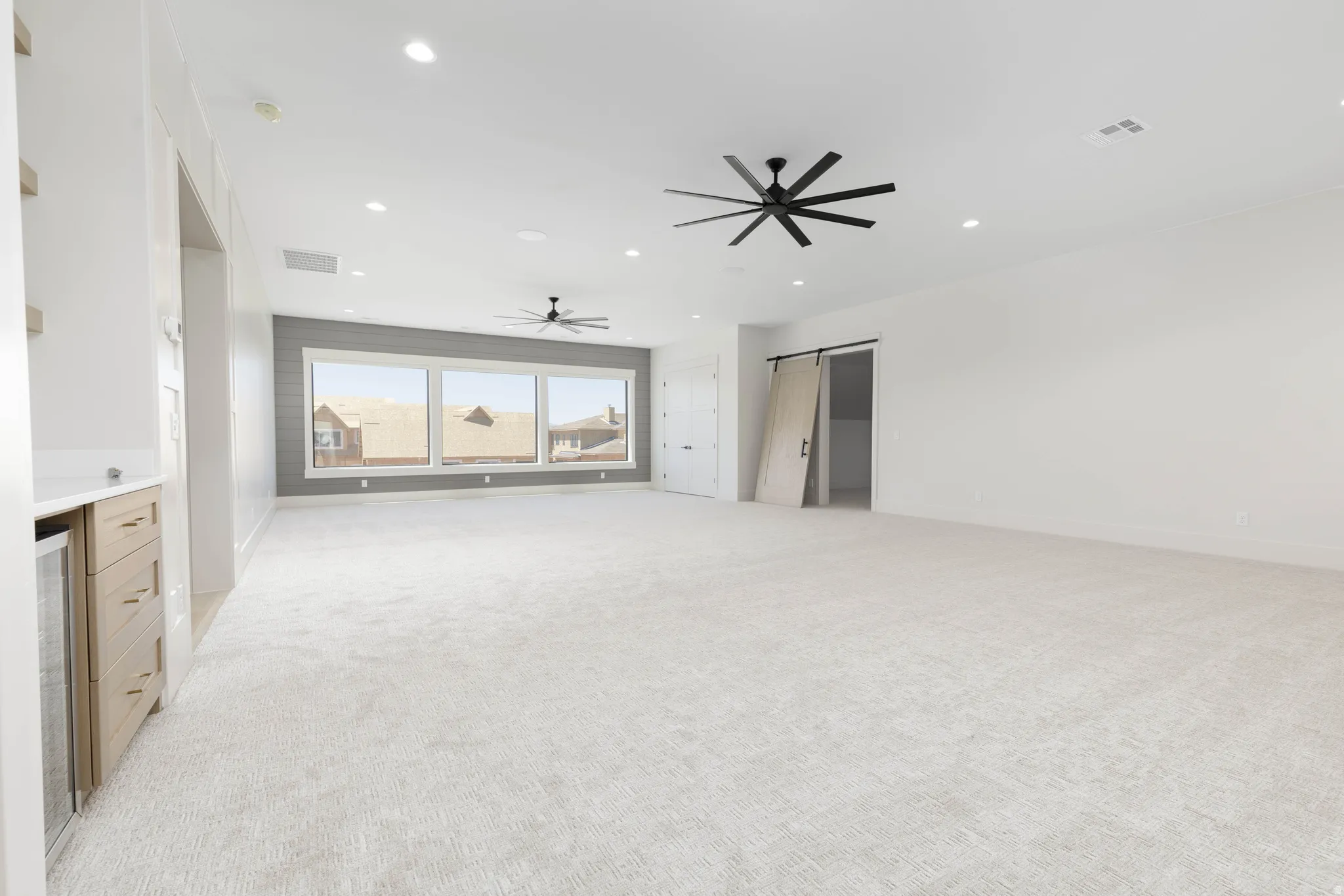 Recessed lighting, light-toned carpeting, and a built-in wet bar with a beverage cooler