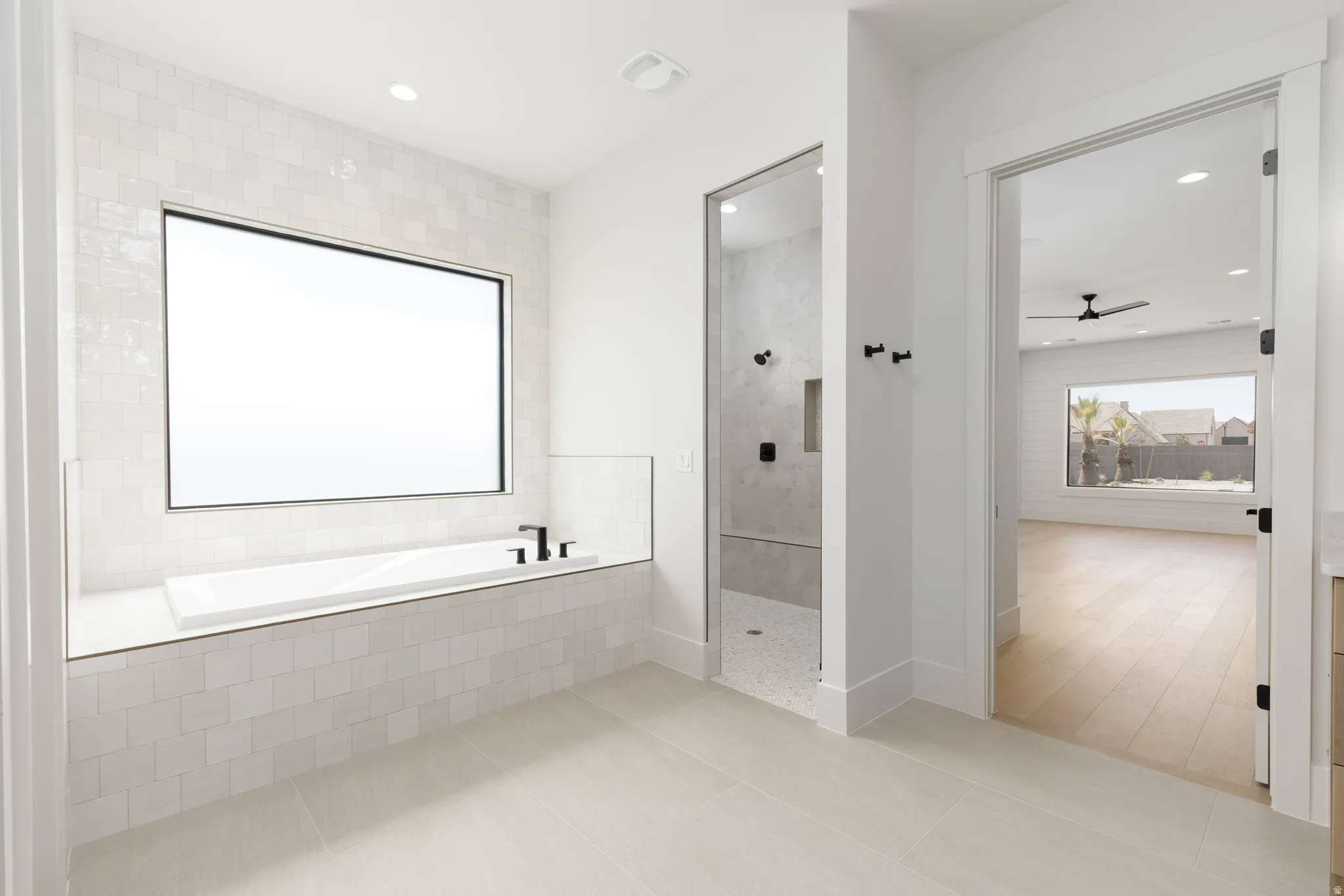 Freestanding soaking tub with matte black fixtures, set within a tiled surround