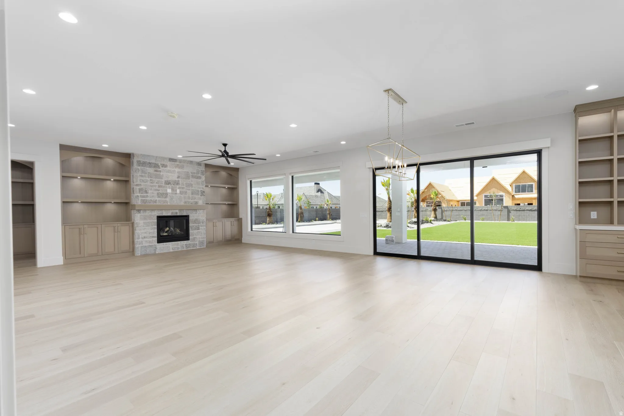 Light wood-finish flooring with recessed lighting and a ceiling fan