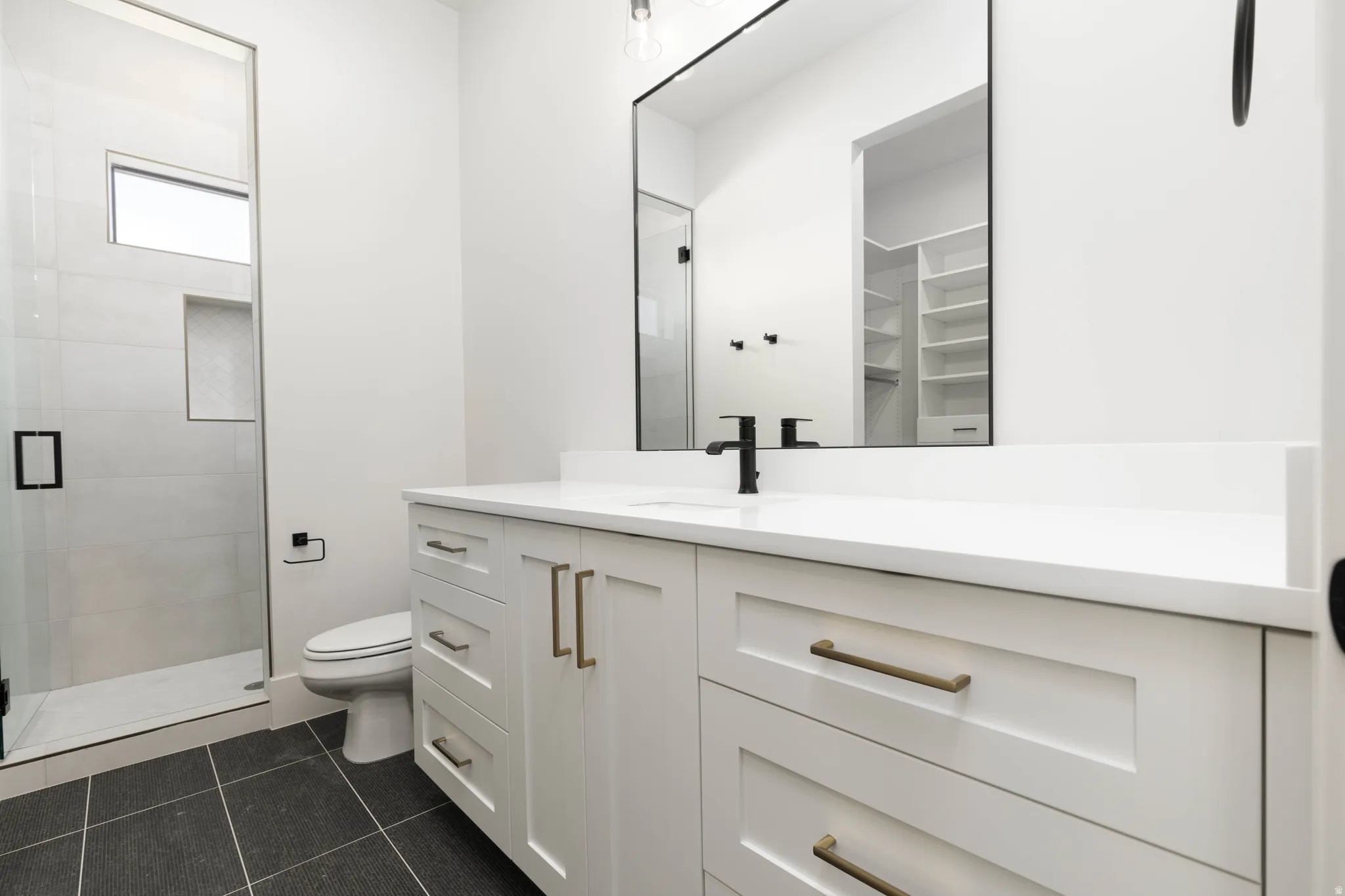 White vanity with a quartz countertop, frameless mirror, and matte black faucet