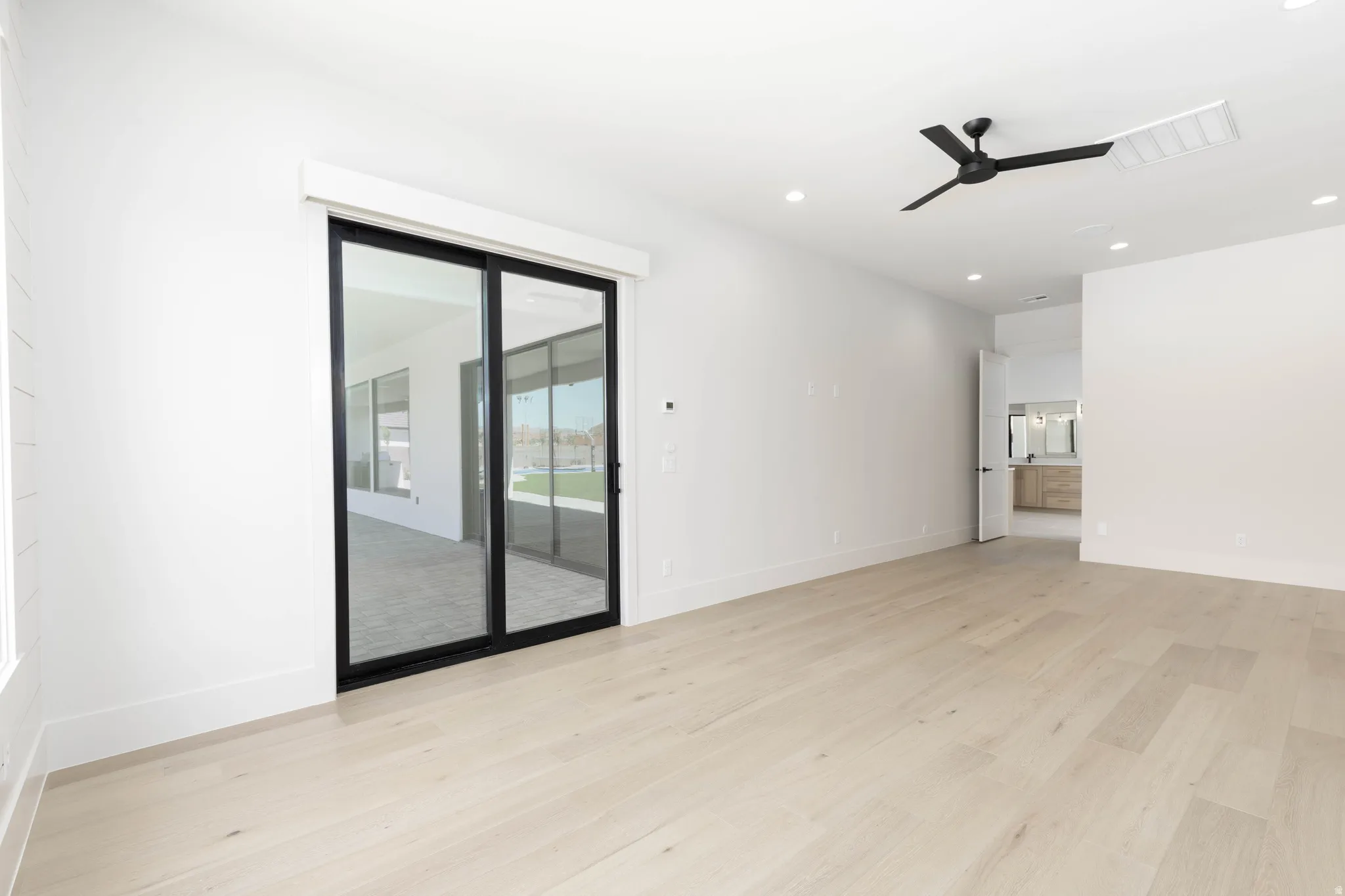 Spacious interior featuring light wood-finish flooring, recessed lighting, and a modern ceiling fan