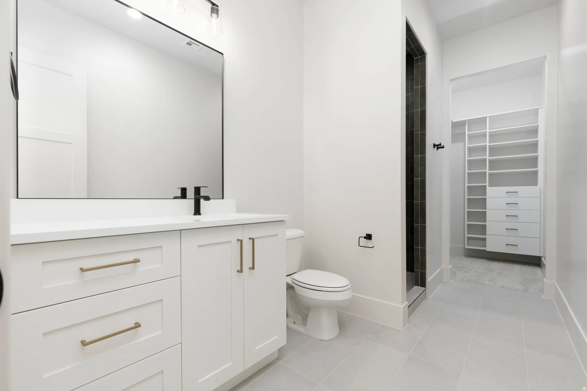 White vanity with a solid surface countertop, matte black faucet, and large rectangular mirror