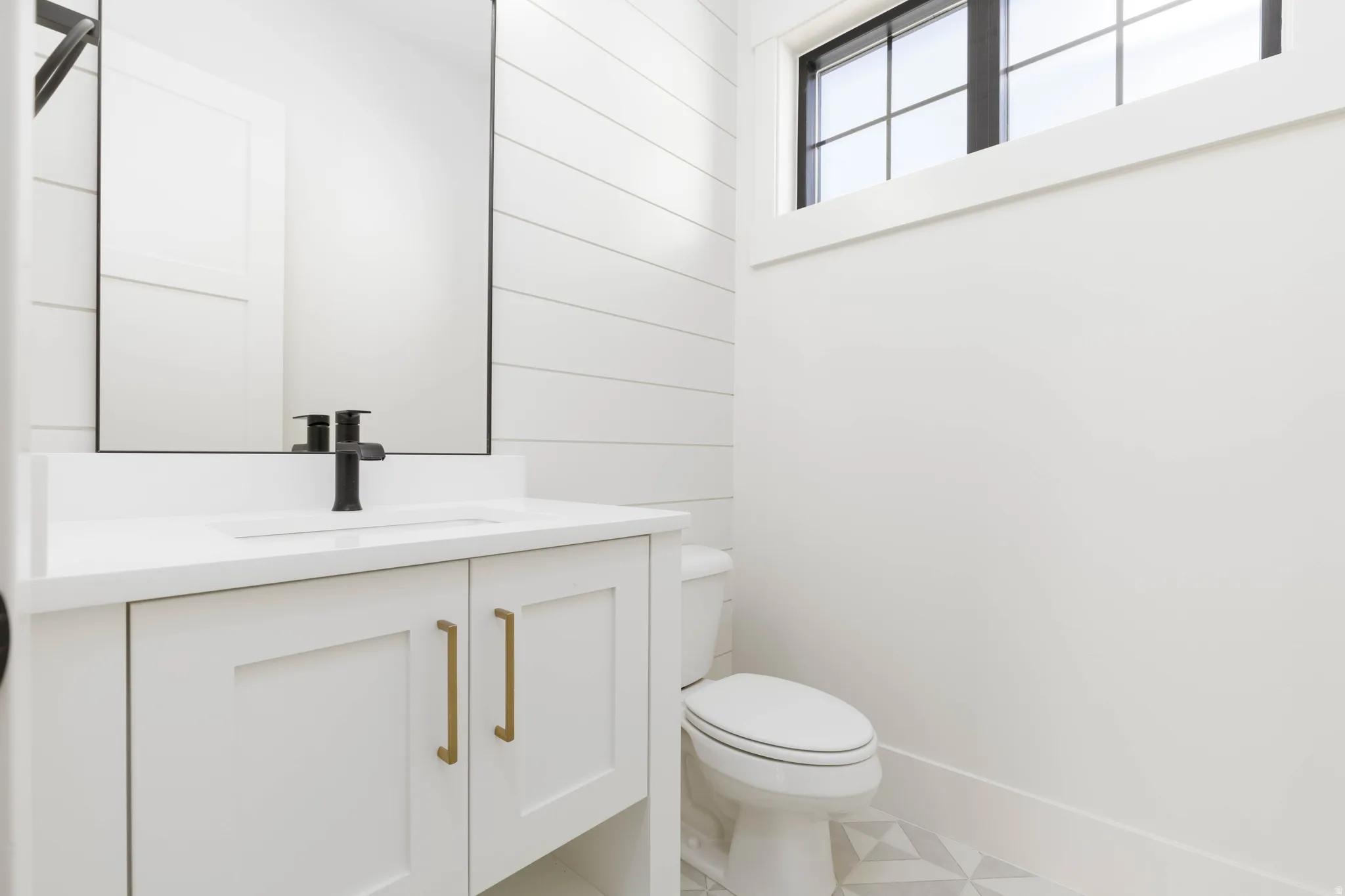 White shaker vanity with gold-tone hardware, rectangular undermount sink, black-finish faucet, and coordinating mirror
