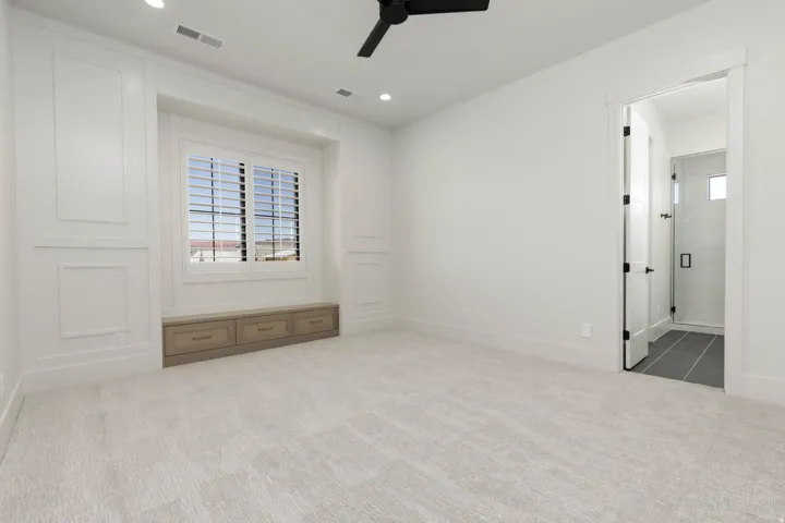 Recessed lighting, ceiling fan, built-in window seat with storage drawers, plantation shutters, and a glass-enclosed shower with tiled walls