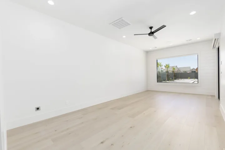 Light wood-finish flooring with recessed lighting and a ceiling fan
