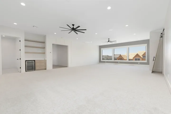 Spacious room featuring light-toned carpet, recessed lighting, and multiple ceiling fans
