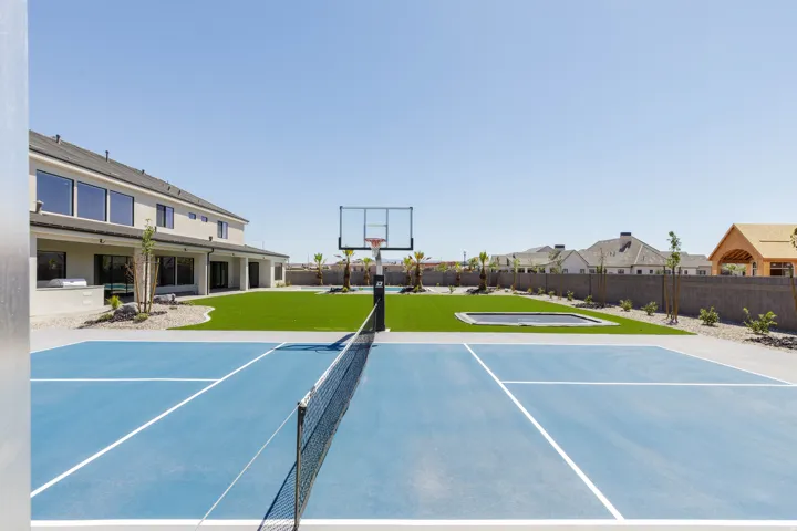 Multi-sport court, artificial turf lawn, basketball hoop, built-in trampoline, and stucco exterior