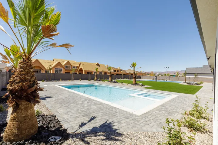 Outdoor living area featuring a swimming pool, integrated spa, paver patio, and artificial turf
