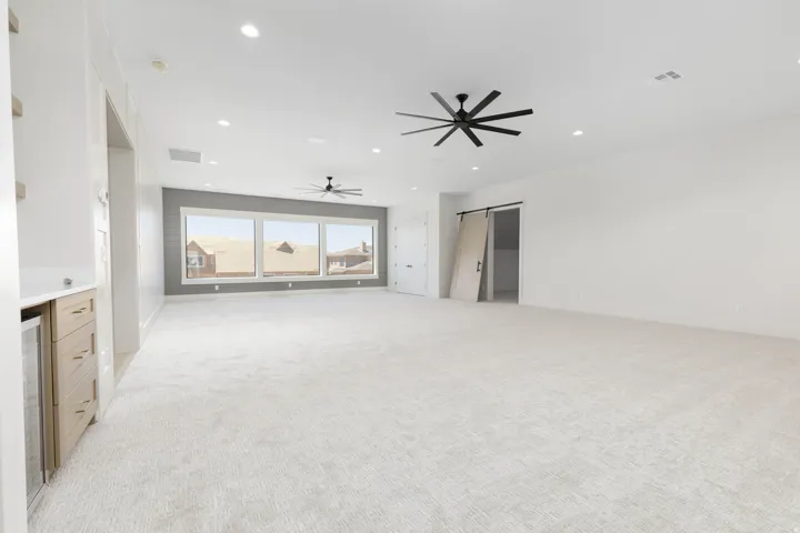 Recessed lighting, light-toned carpeting, and a built-in wet bar with a beverage cooler