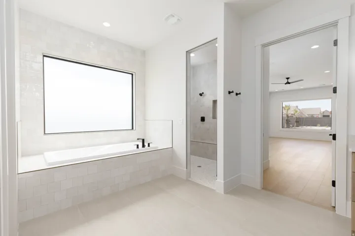 Freestanding soaking tub with matte black fixtures, set within a tiled surround