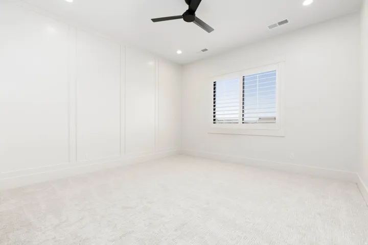 Recessed lighting, ceiling fan, window with plantation shutters, wainscoting, and carpet flooring