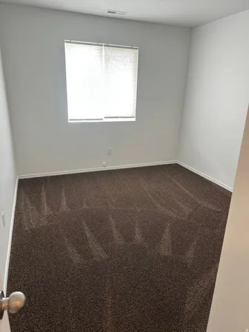 Neutral wall finishes, textured carpeting, and a window with blinds
