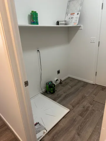 Utility area featuring wood-finish flooring and a wall-mounted shelf