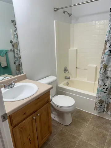 Full bathroom with a wood-finish vanity, integrated sink, and an acrylic tub with a shower fixture