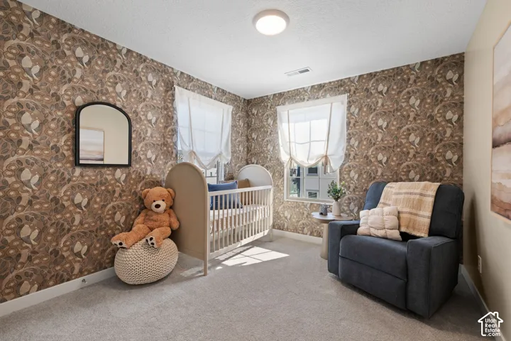 Patterned wallcovering, light-colored carpeting, two windows with Roman shades, and a flush-mount ceiling light