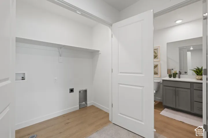 Dedicated laundry area with a white wall shelf, wood-finish flooring, and bright white walls