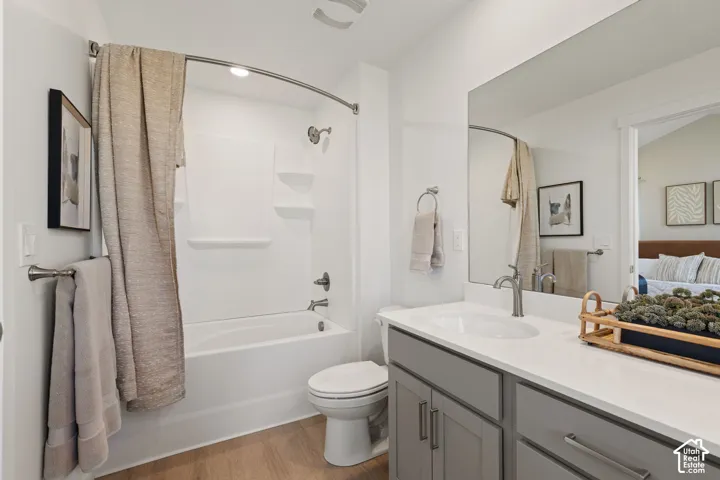 Bathroom featuring a white tub/shower combination, light wood-finish flooring, a vanity with a white countertop, and a large wall mirror