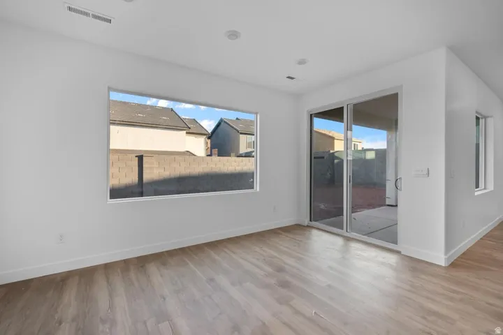 Wood-finish flooring, recessed lighting, expansive rectangular window, sliding glass door, and white walls