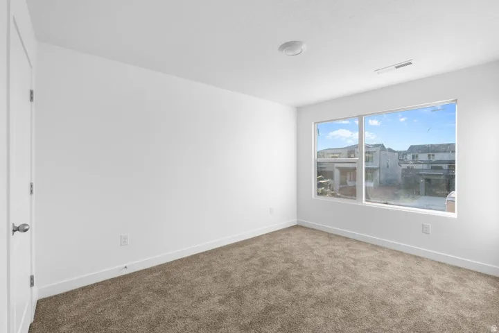 Room with neutral carpet, white walls, and a large window