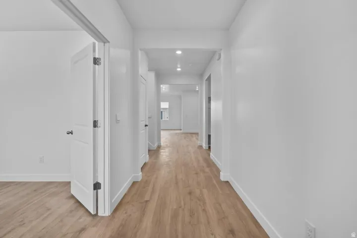 Hallway featuring wood-finish flooring, recessed lighting, and crisp white walls