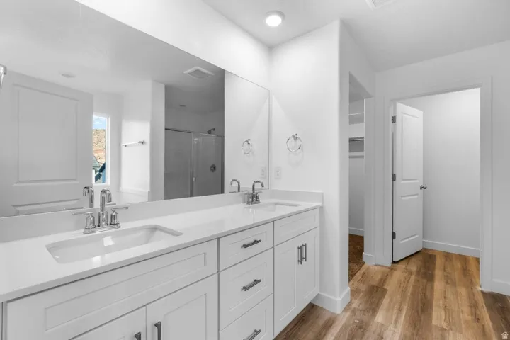 Dual vanity with integrated sinks, white cabinetry, chrome fixtures, and a large wall-mounted mirror