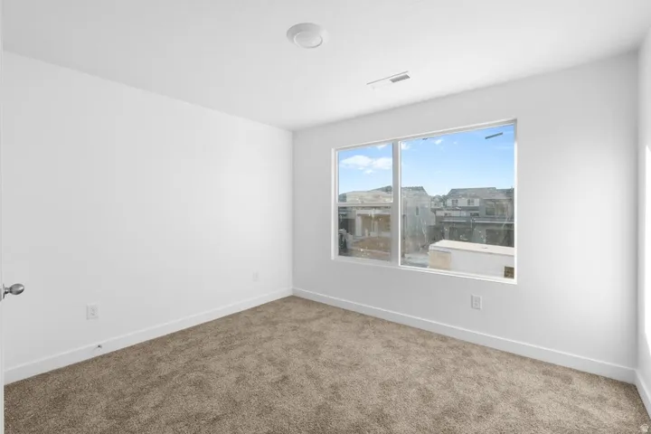 Wall-to-wall carpeting, large window, and overhead lighting