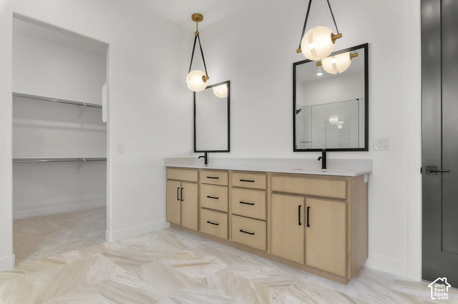 Dual vanity with light wood-finish cabinetry, matte black hardware, and integrated sinks