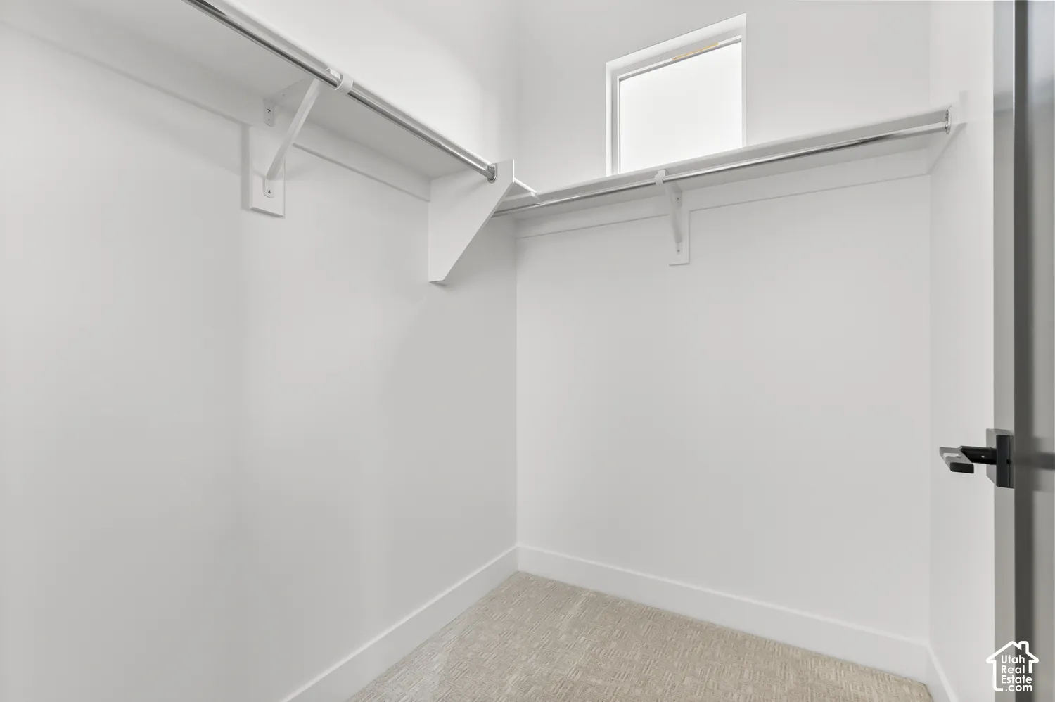 Recessed window, built-in shelving, chrome hanging rods, neutral wall color, and light-toned carpet flooring