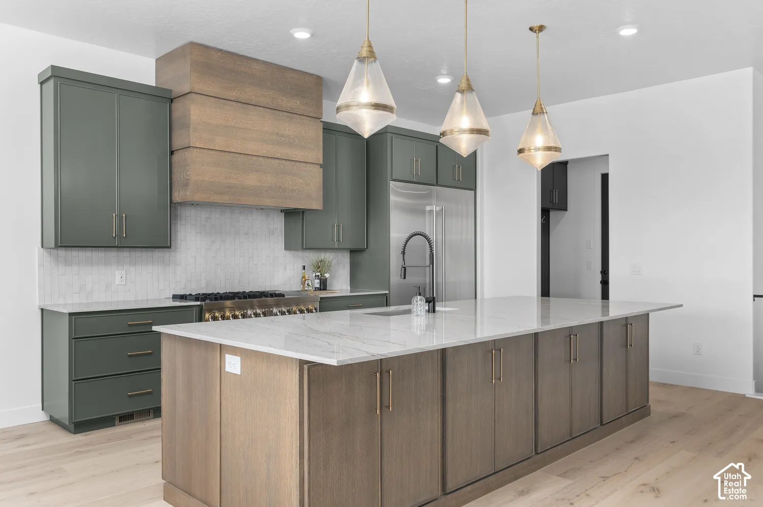 Central island with a light-toned countertop, wood-finish base cabinetry, and pendant lighting