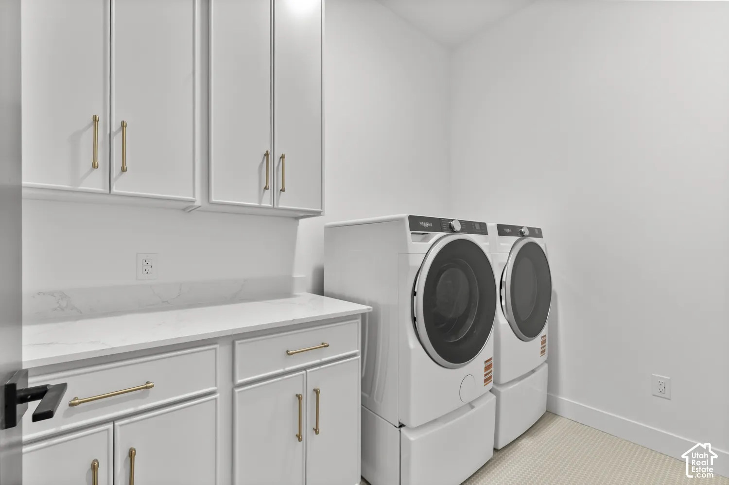 White cabinetry with gold-tone hardware, white countertop, and white walls