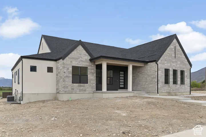Modern architectural design featuring varied exterior finishes, a dark shingle roof, black-framed windows, and an inviting covered entry