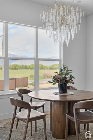 Large picture windows, contemporary chandelier with glass accents, light wood-finish flooring, white wall paint