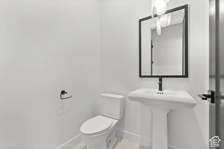 Pedestal sink with a sleek black faucet, a framed mirror, and a white toilet