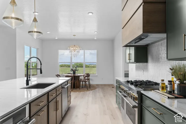 Spacious kitchen featuring a large island with sink, white countertops, light wood-finish flooring, and built-in appliances