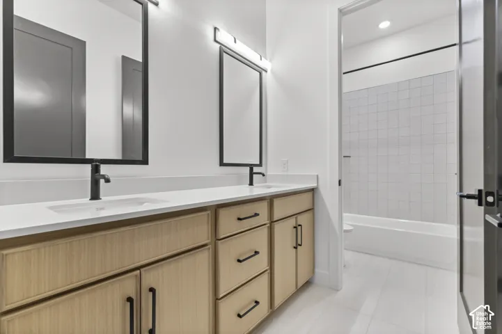 Dual vanity with light wood-finish cabinetry, matte black fixtures, rectangular sinks, and white countertops