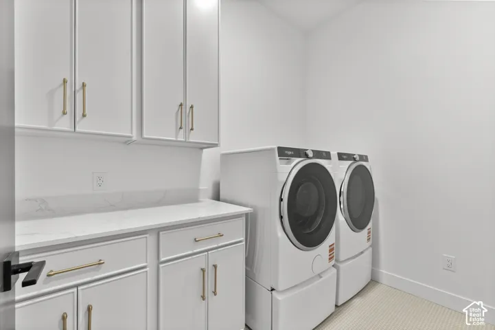 White cabinetry with gold-tone hardware, white countertop, and white walls