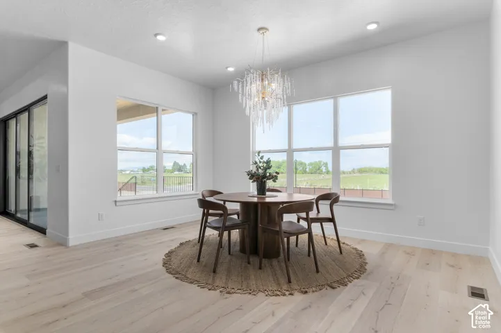 Light wood-finish flooring, recessed lighting, and a modern chandelier illuminate the interior