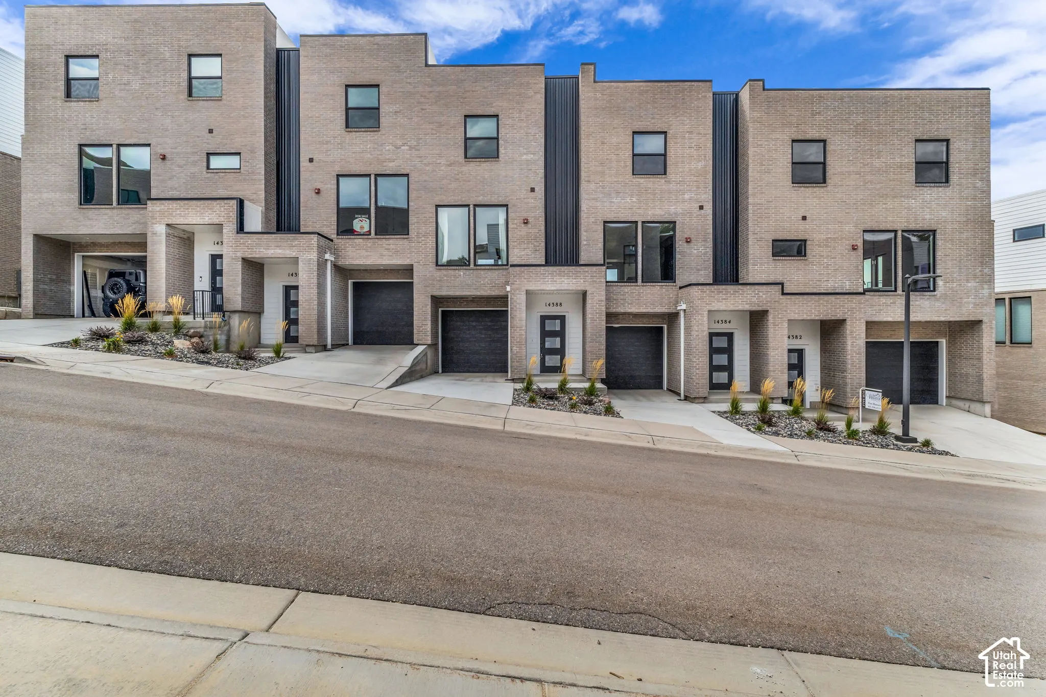 Contemporary brick facade with dark-framed windows, integrated garage, and paved driveway