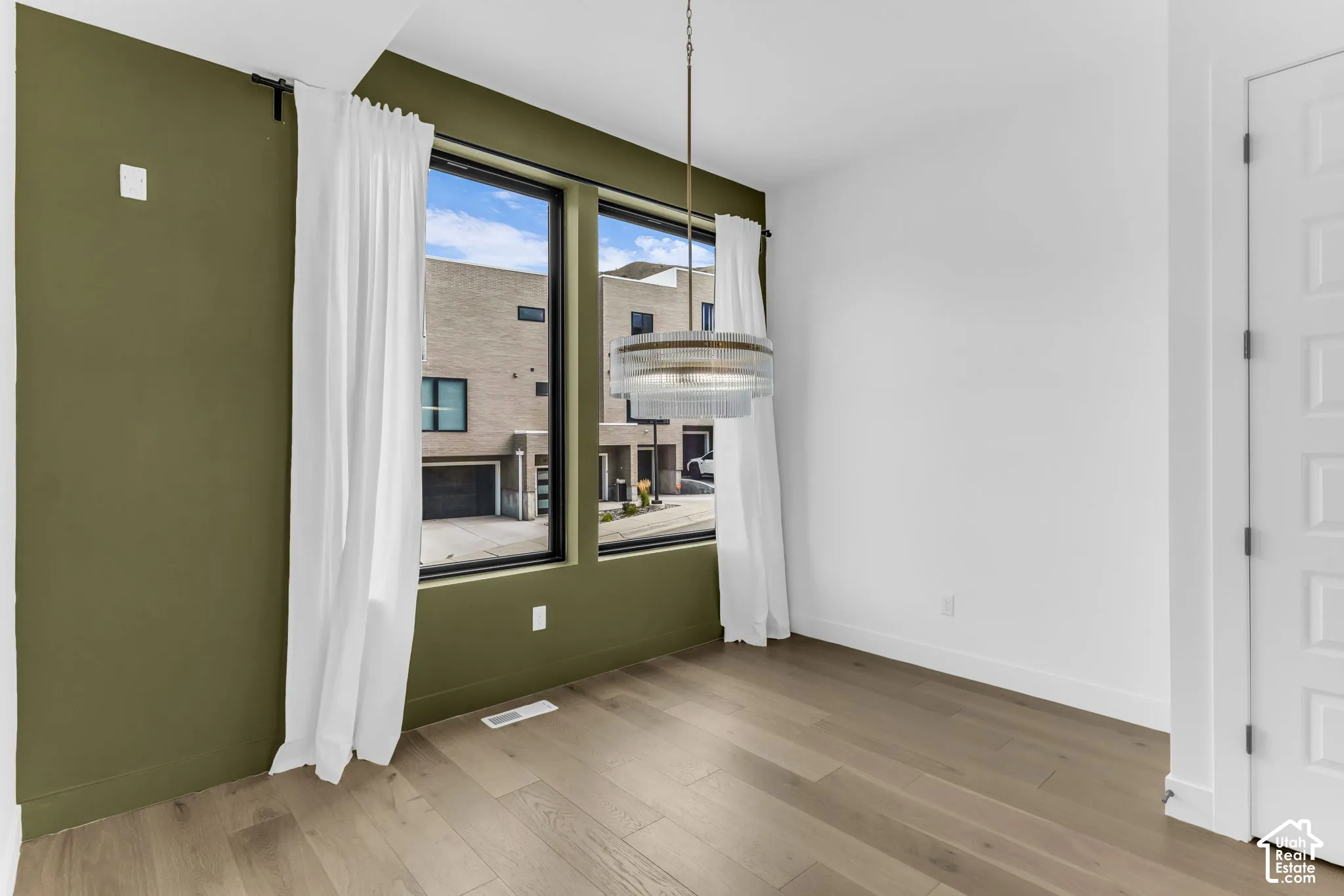 Hardwood-finish flooring, accent wall, modern pendant light fixture, white interior walls, and contemporary window design