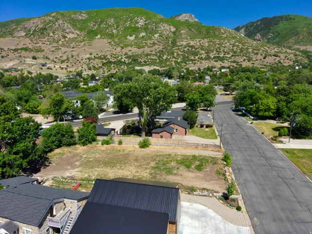Mountain backdrop, residential area, paved road, mature trees, undeveloped lot