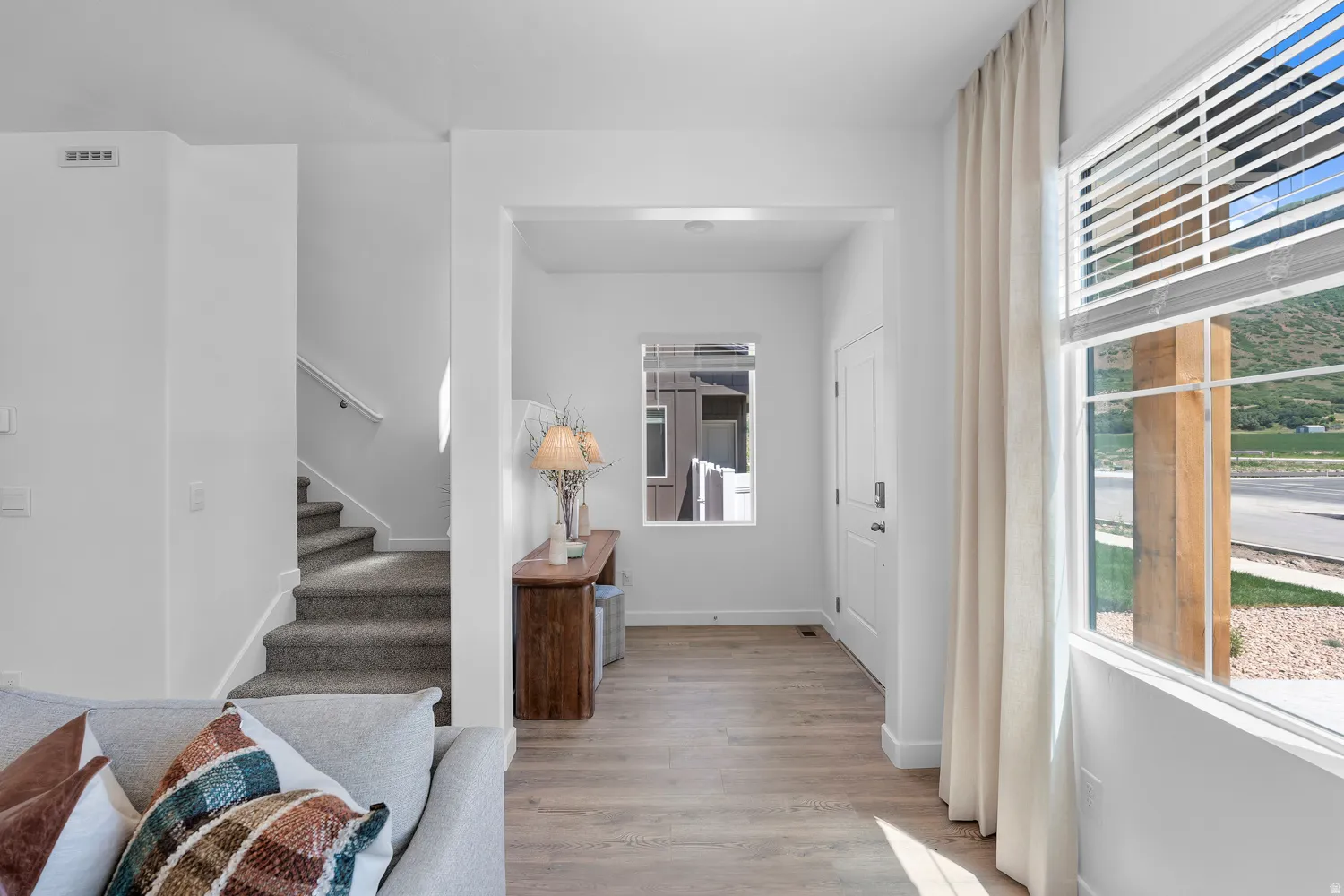Entryway featuring wood-finish flooring, a white paneled door, and a staircase with carpeted treads