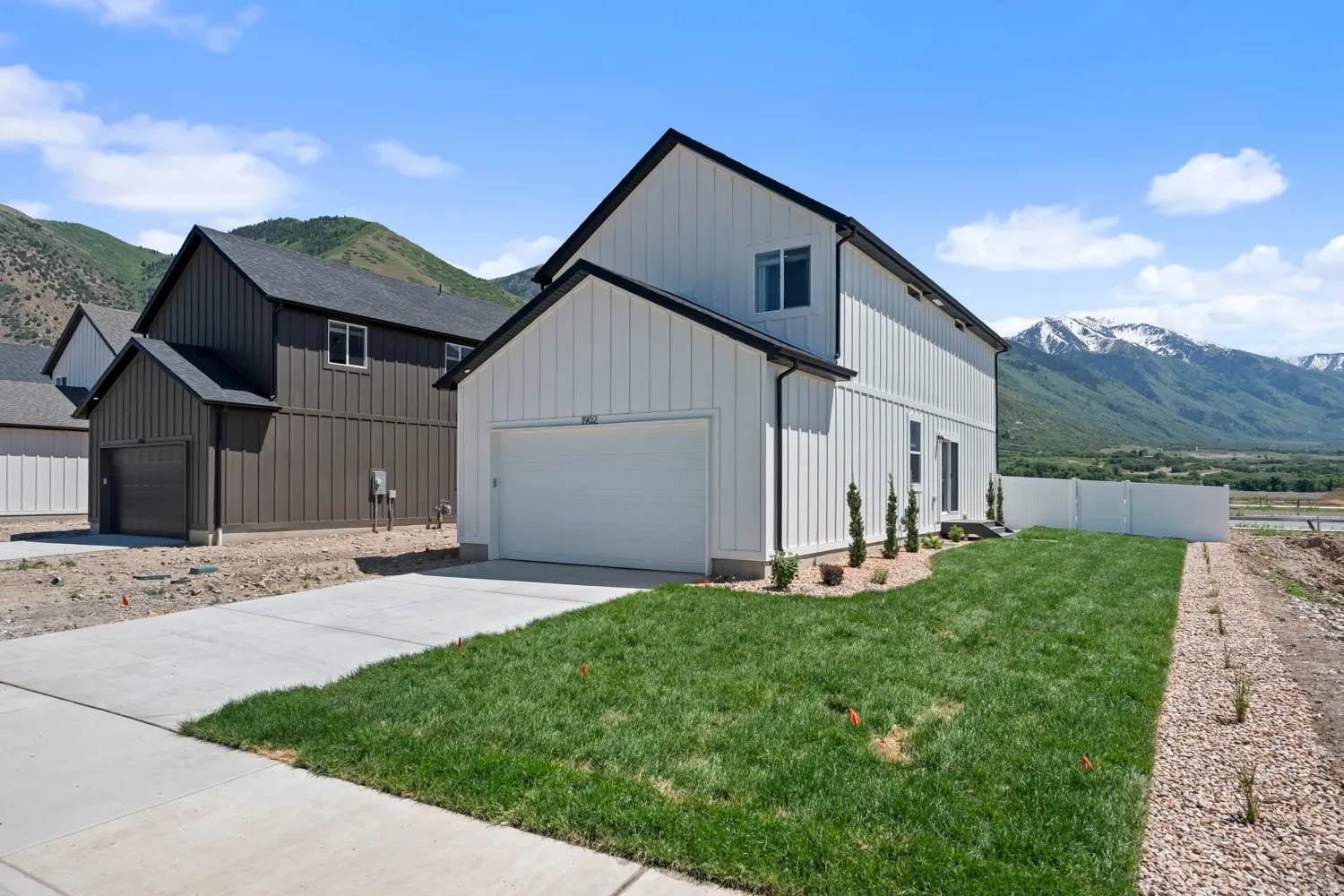 Contemporary two-story residence featuring white board and batten siding, an attached garage, and a concrete driveway