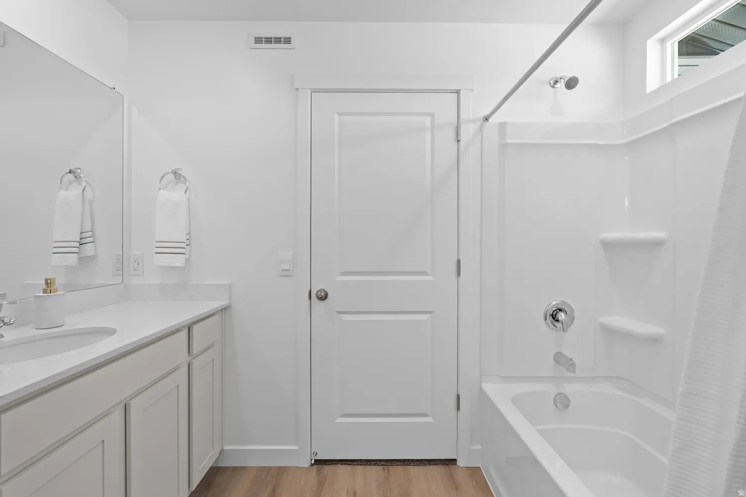 Dual sink vanity with white countertop, white cabinetry, and wood-finish flooring