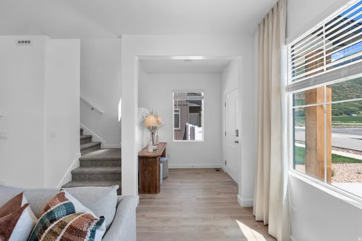 Entryway featuring wood-finish flooring, a white paneled door, and a staircase with carpeted treads