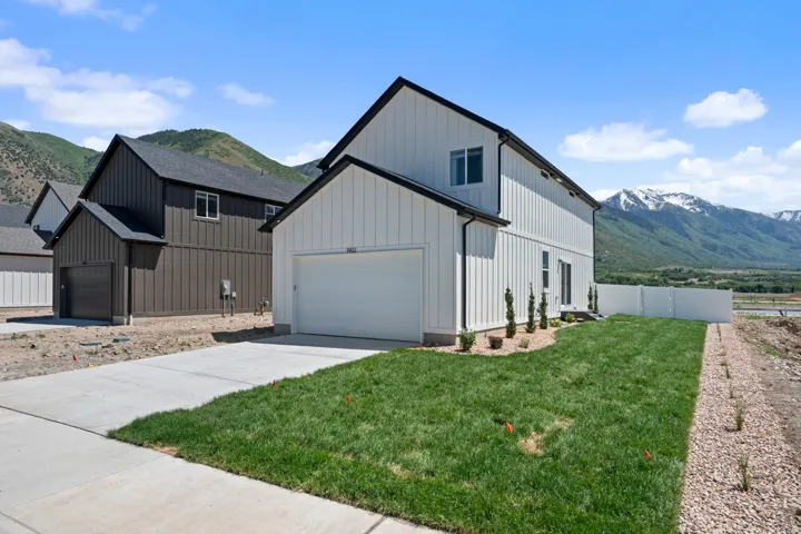 Contemporary two-story residence featuring white board and batten siding, an attached garage, and a concrete driveway