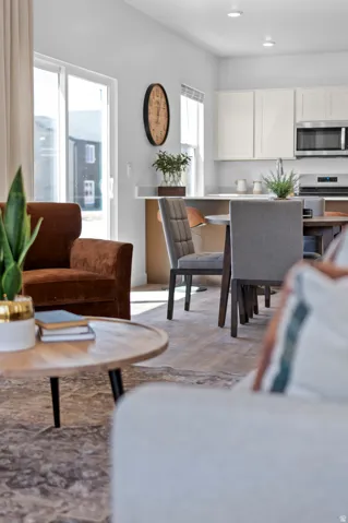 Open-concept living space with wood-finish flooring, white cabinetry, stainless steel appliances, and a sliding glass door