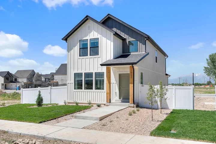 Contemporary two-story residence with white board and batten siding, a dark gray roof, and a welcoming front porch featuring wood-finish posts